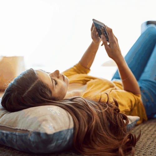 Shot of a young relaxing on the floor and using a smartphone at home