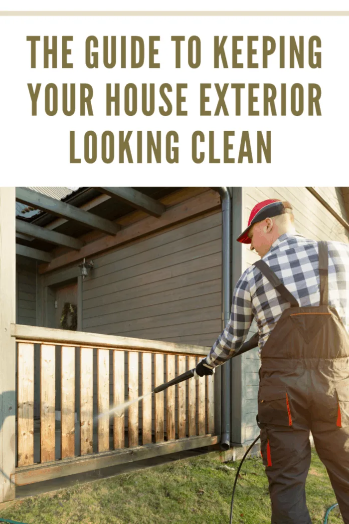 man in overalls pressure washing exterior of home