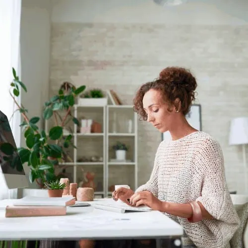 Side view portrait of beautiful mixed-race woman doing freelance work at computer in home office