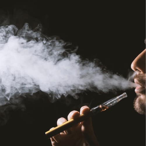 Young man holding and vaping an electronic cigarette, e-cig, ecigarette.