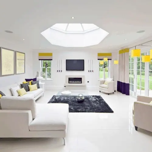 a beautifully furnished morning room in an expensive new home dressed in a modern style. A large skylight together with large patio doors allow plenty of light to illuminate the room. The colour theme is predominantly whites and creams with yellow and pru
