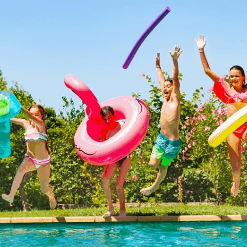 Portrait of age-diverse boys and girls with inflatable swim toys jumping into the water, having fun during summer pool party