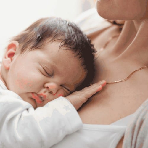Young mother is holding her sleeping newborn baby