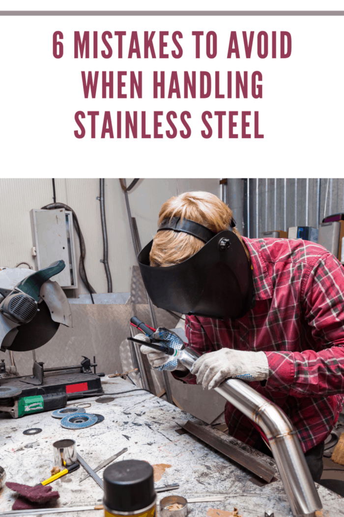 Young guy welder in a checkered red shirt welds a stainless steel pipe for car exhaust using agronomic welding to protect his eyes with a mask in an iron workshop. Modern welding methods.