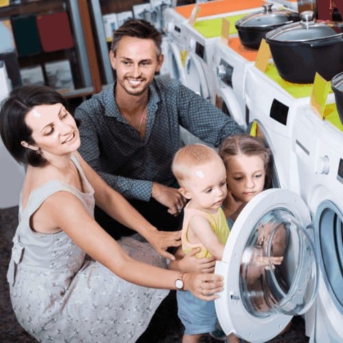 cheerful spanish parents with two kids choosing washing machine in home appliance store