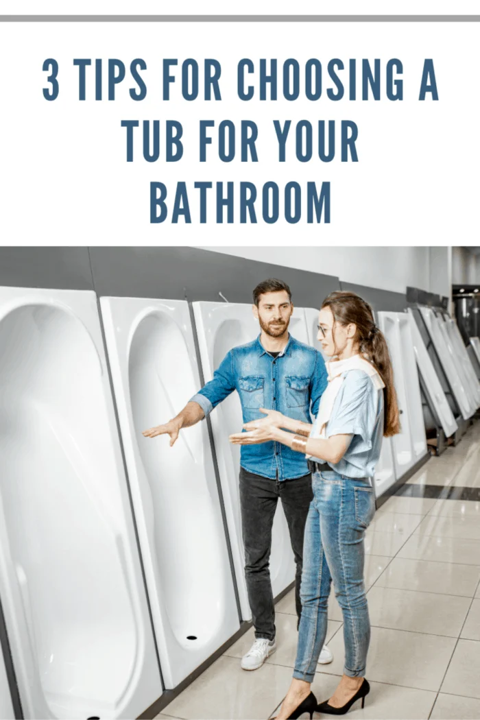 Young couple choosing new bathroom furniture standing near the showcase with white acrylic bathtubs in the plumbing shop