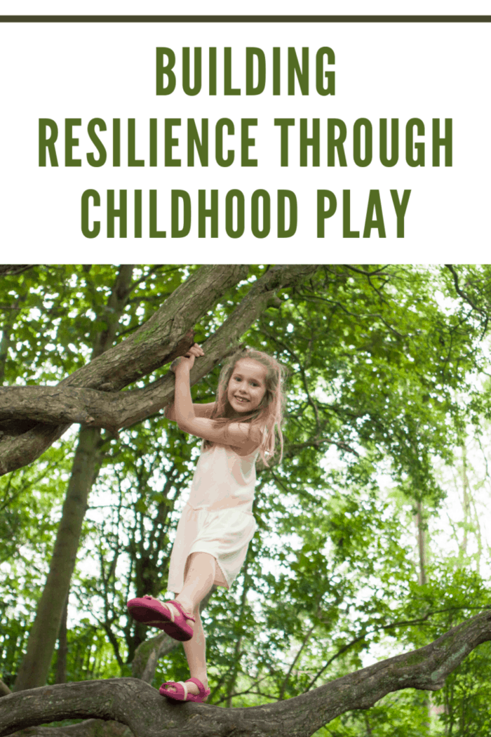 A happy little girl is climbing a tree in a wooded area