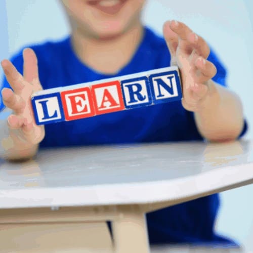boy holds blocks that spell learn as a Concept of early education