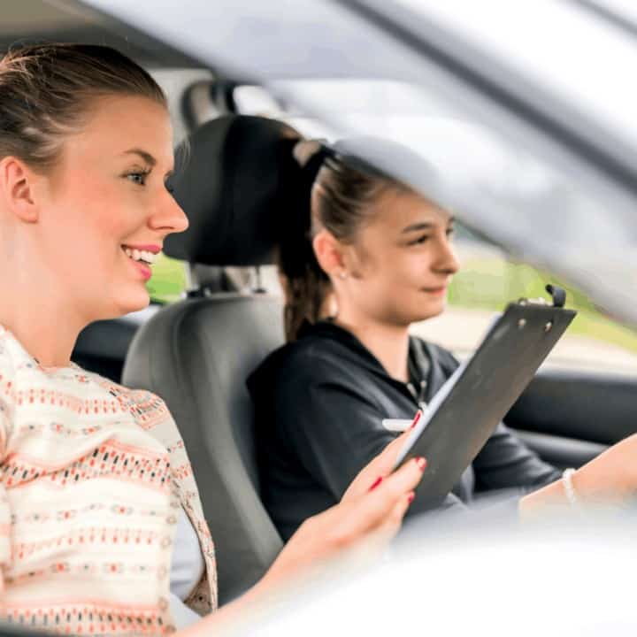 Teen Girl Learns Driver's Education in Car with Adult brown hair woman using clipboard,,, Young Teen Girl Doing Driving Exam with female Examiner while holding Checklist during bright day.