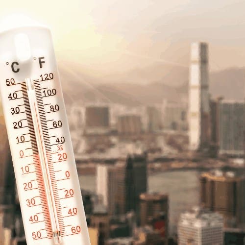 Thermometer in front of an urban skyline during Texas heatwave