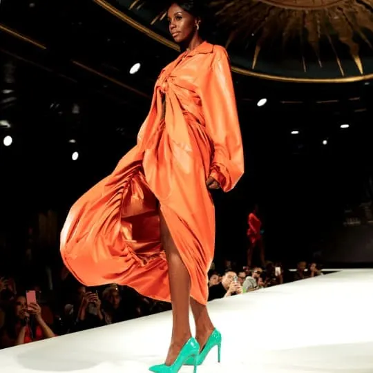Woman in Orange Long Sleeve Dress Standing on White Floor