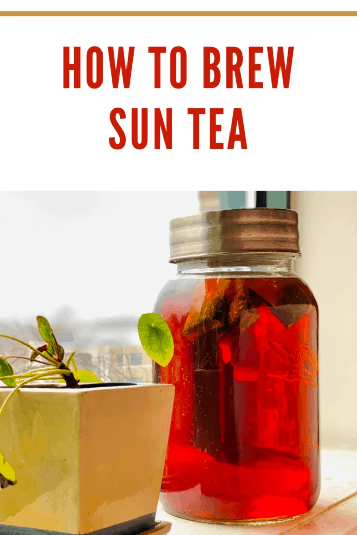 A jar of homemade sun tea sits on a weathered wooden deck with sunshine highlighting it
