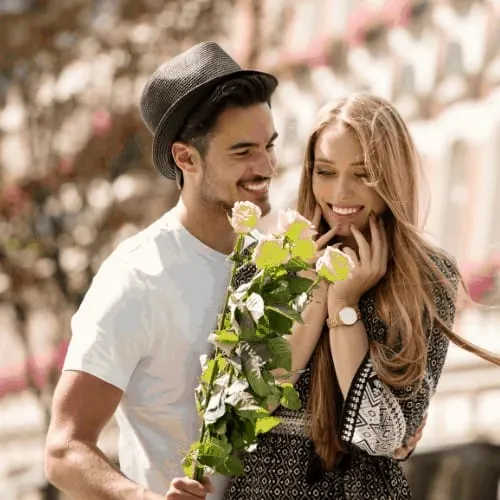 Beautiful young couple with bouquet of roses dating outdoors. Happy blonde attractive girl with handsome man.