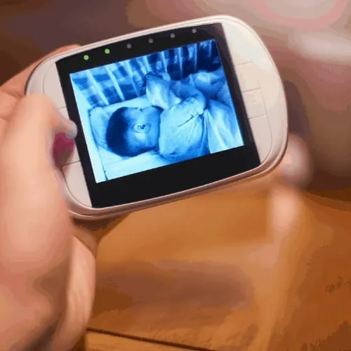 Parent holding the baby monitor looking at the image of the baby sleeping on the screen
