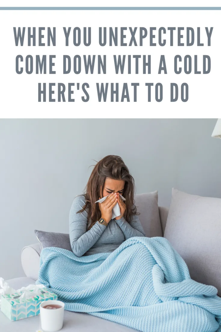 woman with cold under blanket blowing nose into kleenex