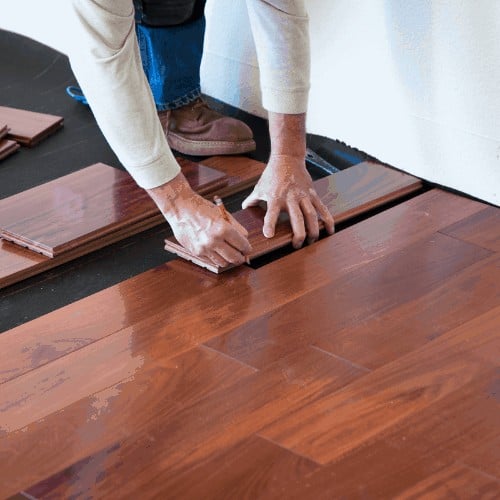 A worker installing hardwood floor in an American upscale home.A worker installing hardwood floor in an American upscale home.
