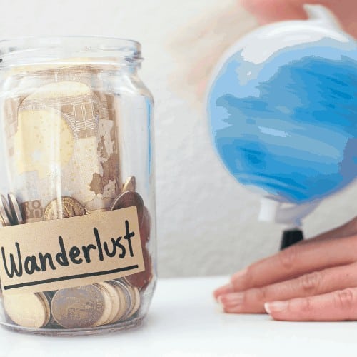 Saving up money to travel concept / Money jar with wanderlust note and rolling world map globe.