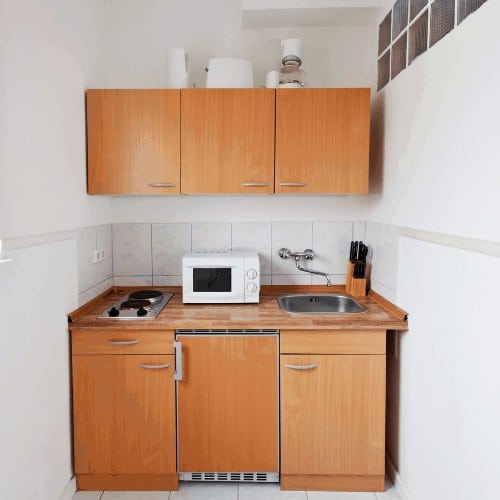 Small kitchen with wooden counters and white walls, appliances and cooking equipment