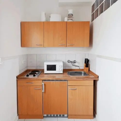 Small kitchen with wooden counters and white walls, appliances and cooking equipment