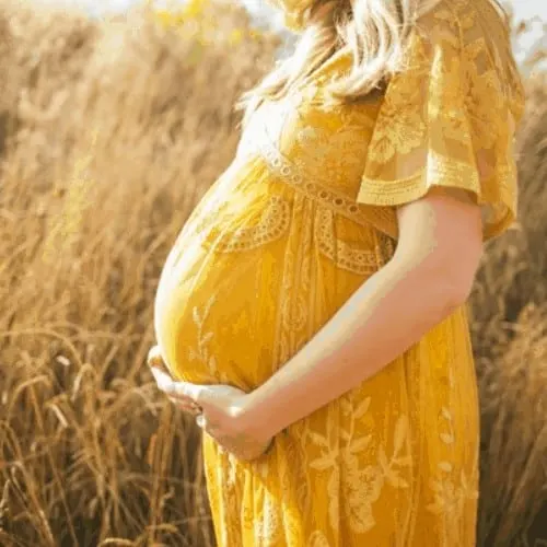 pregnant woman in yellow dress in wheat field