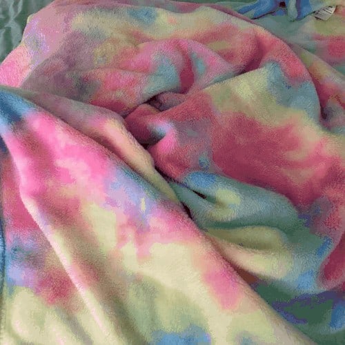 tie dye rainbow blanket piled