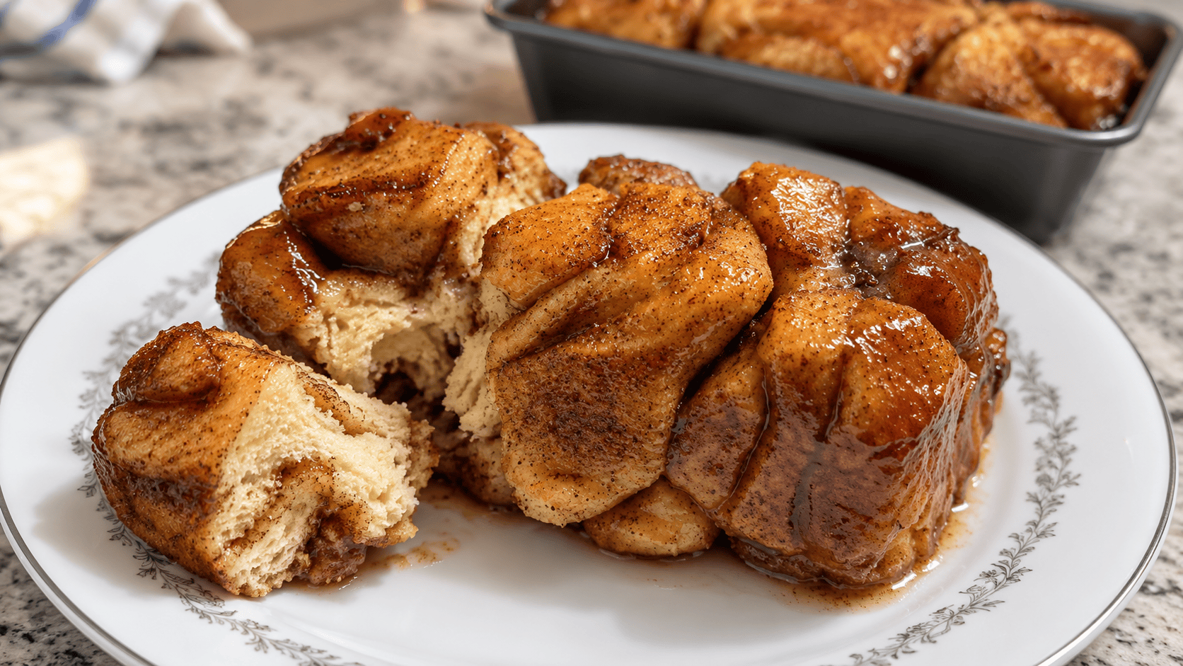 Instant Pot caramel monkey bread on a floral plate, with one piece pulled away to reveal its soft cinnamon-swirled interior.