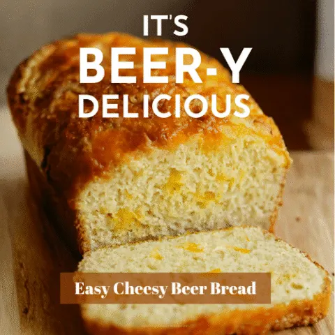 Golden loaf of cheesy beer bread sliced to reveal melted sharp cheddar inside, styled on a rustic wooden board with warm lighting and shallow depth of field.