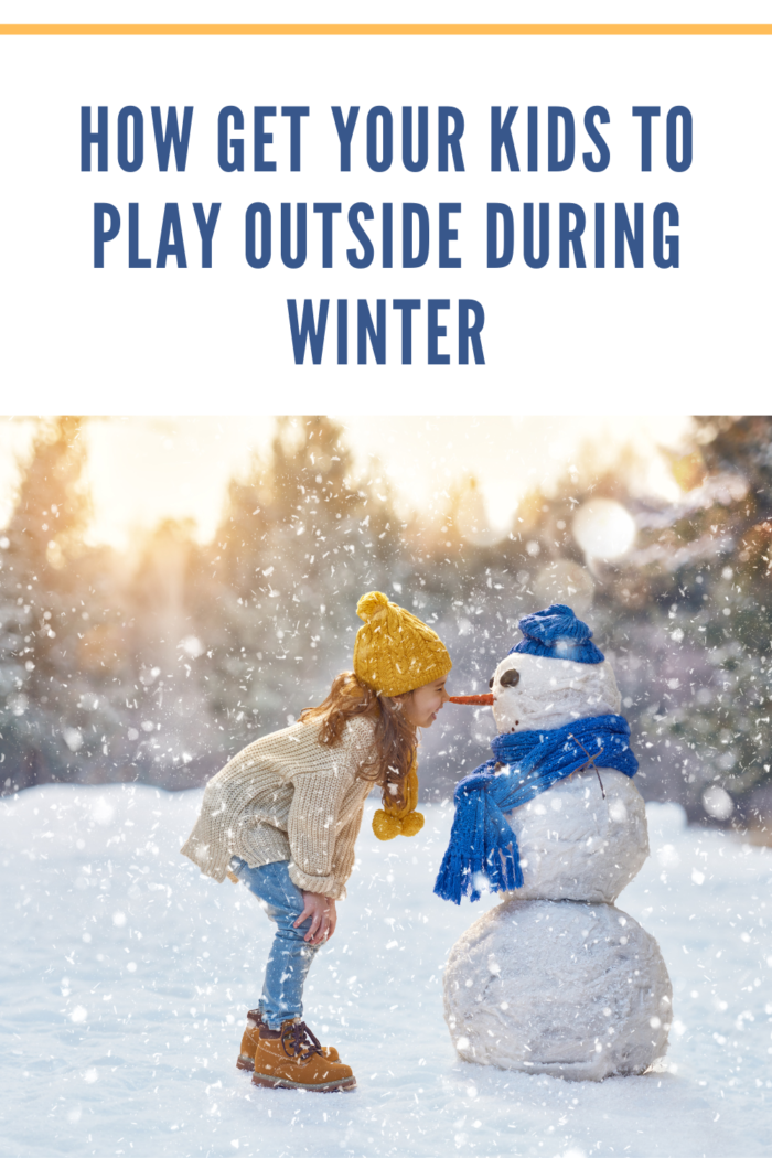 girl playing with snowman in winter