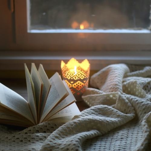 candle next to book in cozy home