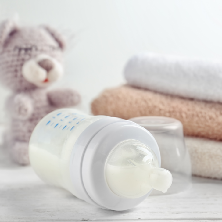 baby bottle with plush toy in background