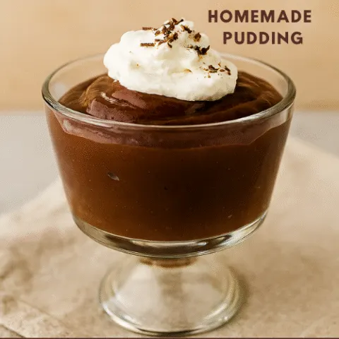 A clear glass dessert bowl filled with glossy homemade chocolate pudding, topped with whipped cream and chocolate shavings, styled on a beige linen cloth with warm lighting and overlay text reading &ldquo;Homemade Pudding &ndash; Easy and whisk-ally delicious.&rdquo;