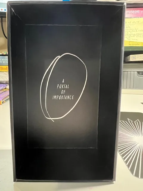 Image showing the interior bottom of The Portent Tarot box with a white oval design and the text 'A Portal of Importance' on a black background.
