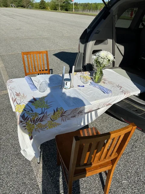 Outdoor romantic table setup for a 'Me-n-U' proposal, featuring a beautifully laid table with a male shadow casting over, positioned in an empty parking lot.