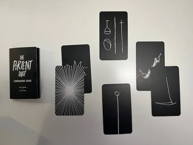 Image showing The Portent Tarot cards face up in the Hermit's Guidance layout with detailed artistic illustrations on a white background.