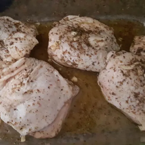 Chicken thighs marinating in spices and herbs for a delicious one-pot chicken and rice meal.