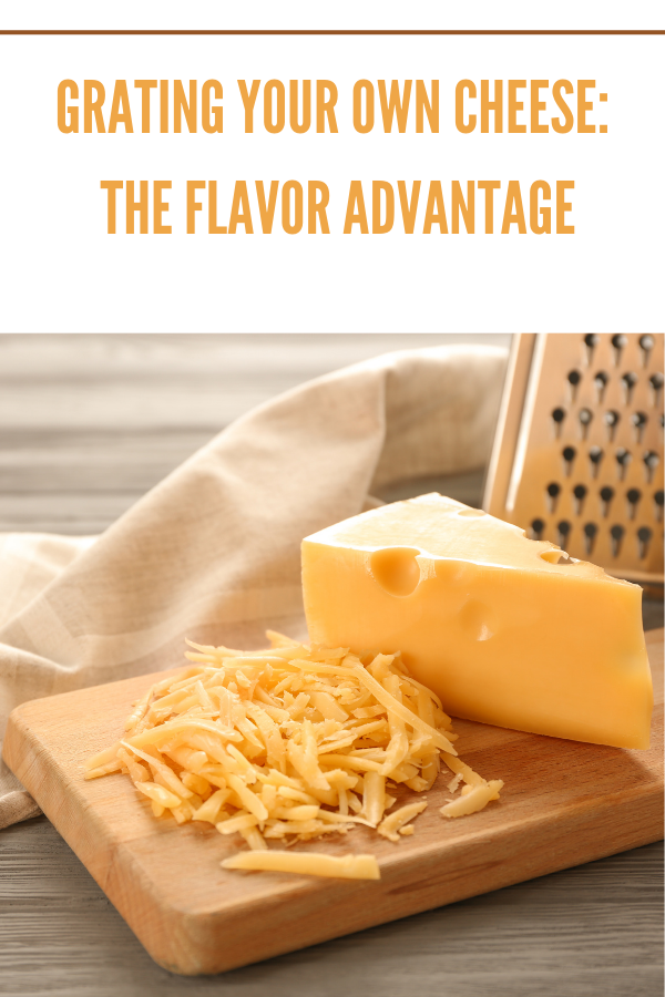 Block of cheddar cheese being freshly grated on a wooden board with a stainless steel grater.