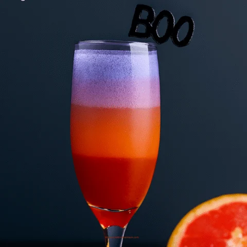 Layered prosecco cocktail in a champagne flute with strawberry red, melon orange, and light violet layers. Garnished with a black &ldquo;BOO&rdquo; stirrer. Text overlay reads &ldquo;A BOO-ZY GOOD TIME&rdquo; with subtitle &ldquo;Layered Prosecco Cocktails&rdquo; against a dark background with a grapefruit slice.