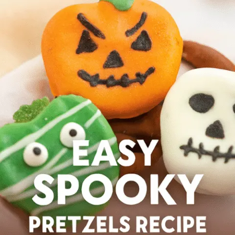 Halloween-themed chocolate-covered pretzels decorated as jack-o-lanterns, mummies, and skulls with candy eyes and icing on a rustic table.