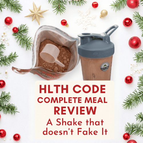 Festive flat lay of HLTH Code chocolate protein powder and BlenderBottle shaker surrounded by pine sprigs, ornaments, and snowflakes. Text overlay reads “HLTH Code Complete Meal Review – A Shake that doesn’t Fake It.”