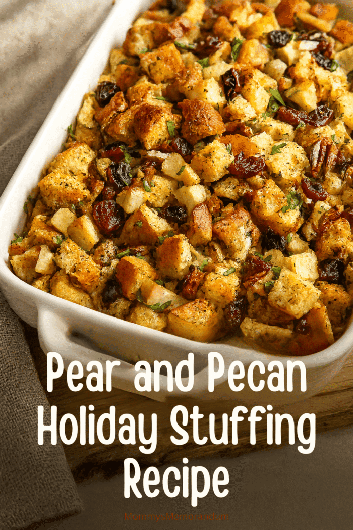 Golden-brown pear and pecan stuffing in a white casserole dish, featuring buttery bread cubes, tender pears, cranberries, and toasted pecans. Styled on a rustic holiday table with warm lighting and cozy autumn props.