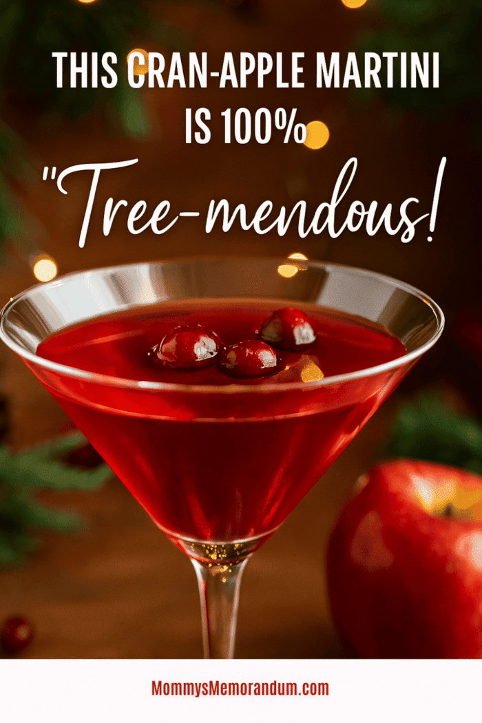 Cranberry Apple Martini garnished with fresh cranberries and a lemon twist, set against a cozy holiday backdrop with twinkling lights and red apple