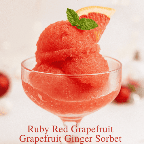 A vibrant scoop of Ruby Red Grapefruit Ginger Sorbet served in a vintage glass coupe, garnished with a slice of grapefruit and fresh mint. The image features soft holiday bokeh with red ornaments in the background and overlay text reading “Frosty, fruity, and full of holiday cheer!” with the subtitle “Ruby Red Grapefruit Ginger Sorbet.”