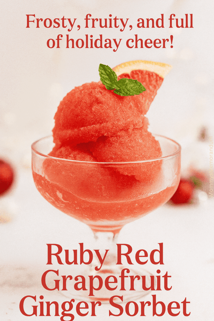 A vibrant scoop of Ruby Red Grapefruit Ginger Sorbet served in a vintage glass coupe, garnished with a slice of grapefruit and fresh mint. Soft holiday bokeh with red ornaments in the background.