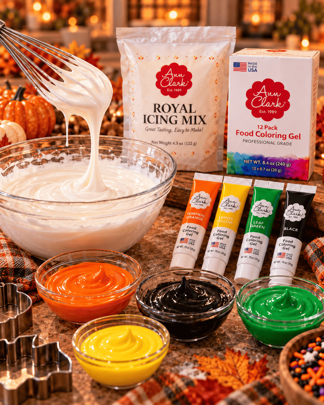 Ann Clark Royal Icing Mix with Pumpkin Orange, Lemon Yellow, Leaf Green, and Super Black food coloring gels beside bowls of tinted royal icing