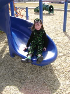 little girl on slide dressed in st patricks' day clothes