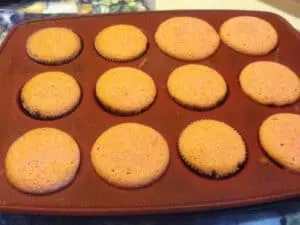 Freshly baked TGIF Strawberry Shortcake Cupcakes cooling on a wire rack, ready for frosting and serving.