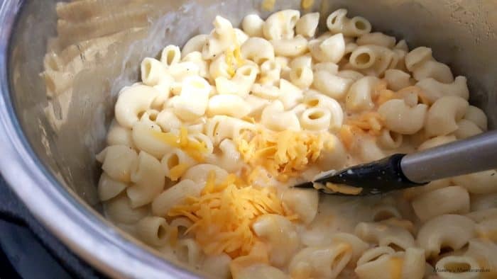 macaroni in bowl being stirred with cheese and sauce