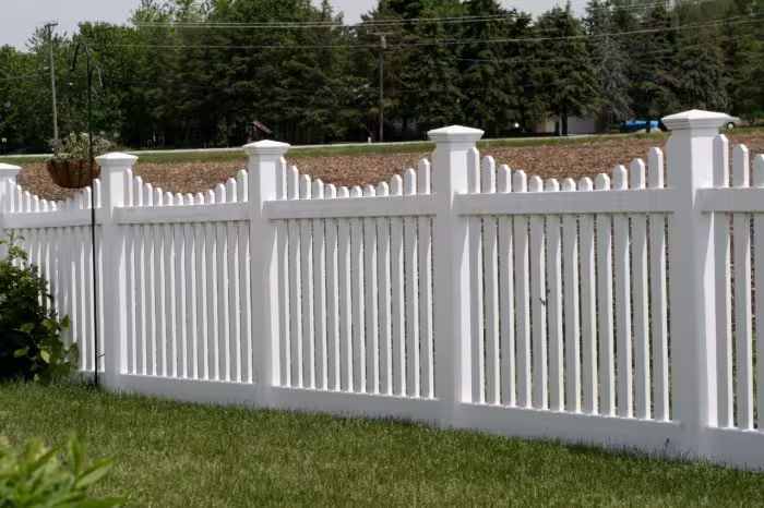 A well-maintained white vinyl fence surrounding a lush green lawn, showcasing its aesthetic appeal and practicality.