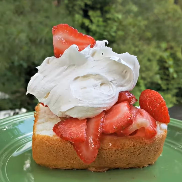 Fluffy angel food cake topped with marshmallow creme and strawberries, a light summer dessert.