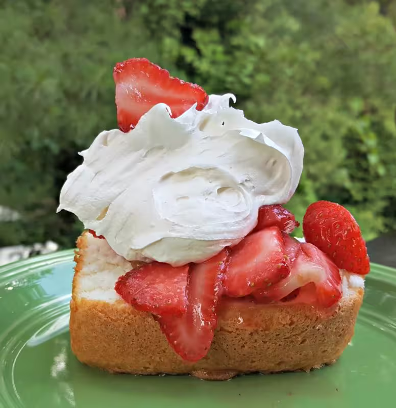 Fluffy angel food cake topped with marshmallow creme and strawberries, a light summer dessert.